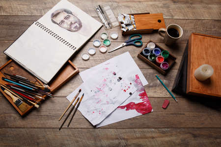 A view of the objects for drawing. Brushes, paints in a box for materials on wooden parquet. Art...
