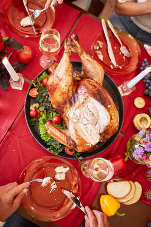Family eating traditional Thanksgiving turkey on a festive table background. Roasted turkey. Family celebration concept.の写真素材