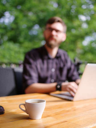 Goodly young man working on laptop while sitting outdoors . Business concept.の写真素材