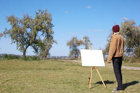 Young artist painting an autumn landscape on the nature background. Art concept.の写真素材