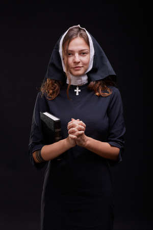 Pretty young nun in religion concept against dark background.の写真素材