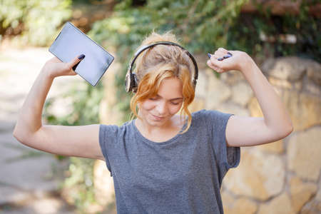 Sunny young girl listening music and walking in the park.の写真素材