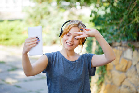 Sunny young girl listening music and walking in the park.の写真素材
