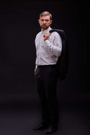 Successful young businessman in a black suit posing on a black background. Business concept.の写真素材