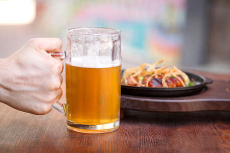 Glass of light beer with with a sausage plate on a dark table.の写真素材