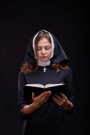 Pretty young nun in religion concept against dark background.の写真素材