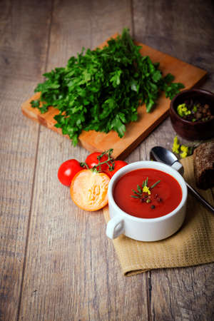 A fragrant red borscht in a white plate with a lots of vegetables on wooden background. Food concept.の写真素材