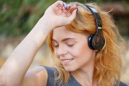 Sunny young girl with headphone walking around the street.