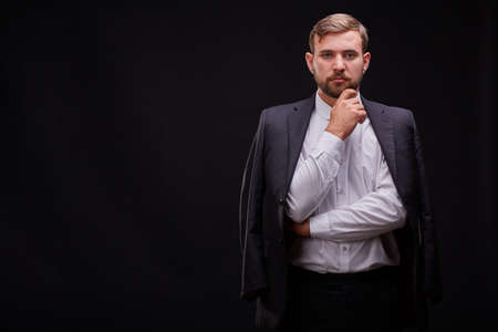 Successful young businessman in a black suit posing on a black background. Business concept.の写真素材