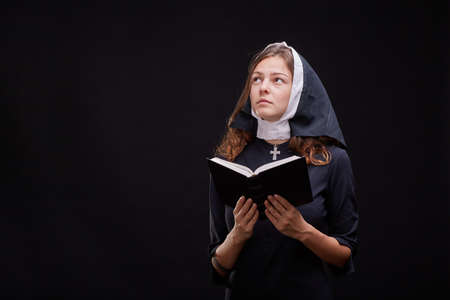Pretty religious nun against dark background. Religion concept.の写真素材