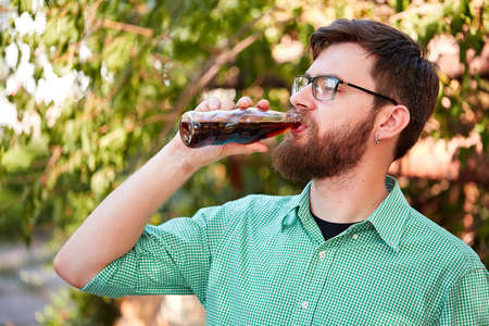 Goodly boy with a glasess tasting delicious food in the park. Nature background.の写真素材