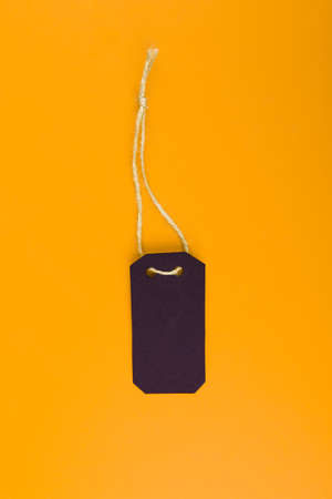 Close-up of a black tag price tag on a bright yellow background. concept of black Fridayの写真素材