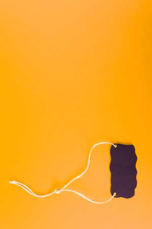 Close-up of a black tag price tag on a bright yellow background. concept of black Fridayの写真素材