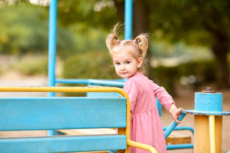 Little girl in a pink dress on a playground.の写真素材