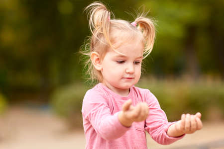 Beautiful little girl in a pink dress playing in the open airの写真素材