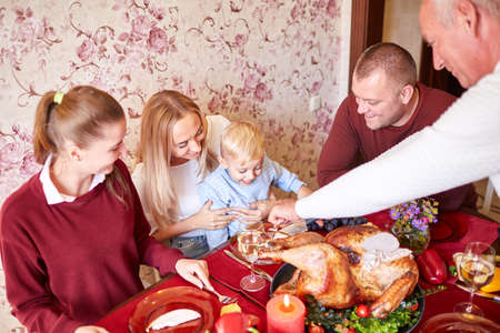 Happy family at the dinner table celebrating Thanksgiving on a blurred background. Traditional Thanksgiving concept.の写真素材