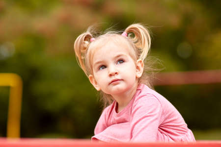 Beautiful little girl in a pink dress playing in the open airの写真素材