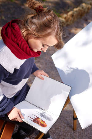 The female artist is painting a picture in the autumn park.の写真素材