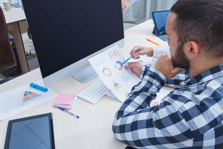 A young man with a beard is working with a scheduleの写真素材
