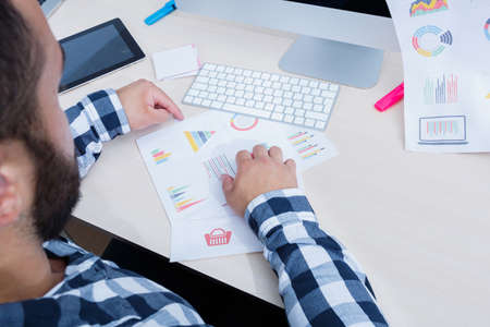 A young man with a beard is working with a scheduleの写真素材