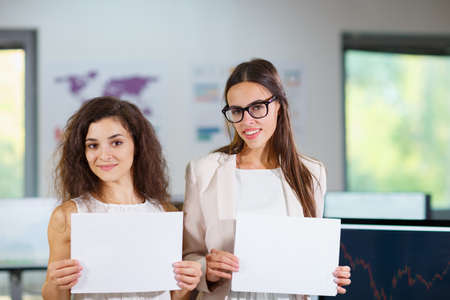 Two cheerful beautiful young business girls in the office.の写真素材