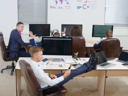 Man sitting in office with legs on table.