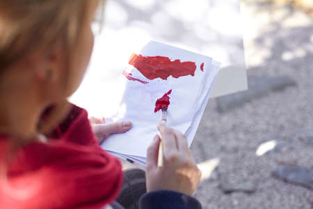 The female artist is painting a picture in the autumn park.の写真素材