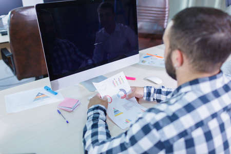 A young man with a beard is working with a scheduleの写真素材