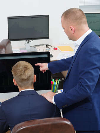 Group of young people in the office looking at the computer screenの写真素材