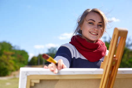 Beautiful girl artist painting a beautiful picture in nature