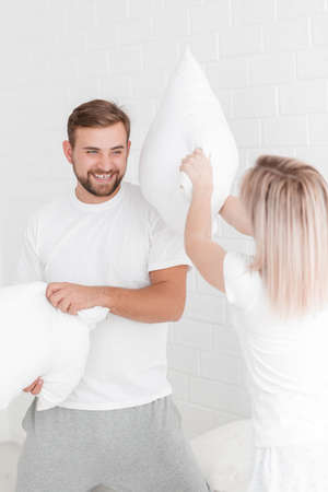 A young couple is beating pillows in the bedroom.の写真素材