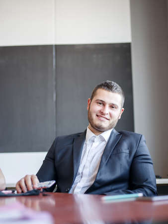 Happy man in the office sitting and posing on the camera . Business concept.の写真素材