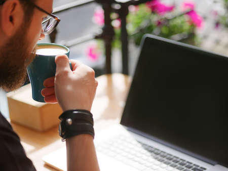 Goodly young man working on laptop while sitting outdoors . Business concept.の写真素材