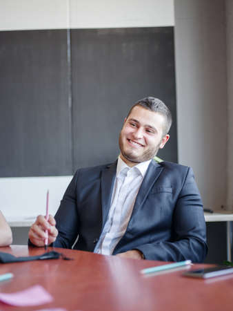Happy man in the office sitting and posing on the camera . Business concept.の写真素材