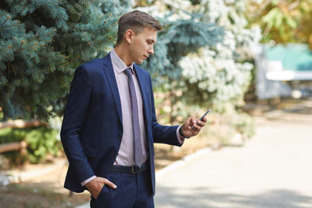 Goodly young man working in the park and posing on camera. Business concept.の写真素材