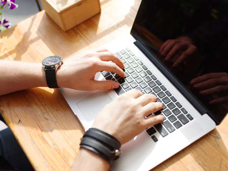 Goodly young man working on laptop while sitting outdoors . Business concept.の写真素材