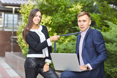 Pretty girl and handsome guy work in the park on a computer on a natural background.の写真素材