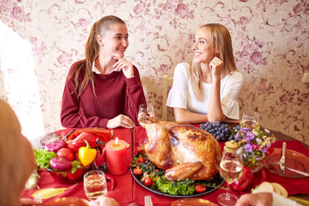 Happy sisters at the family festive Thanksgiving dinner on a light background. Domestic celebrating concept.の写真素材