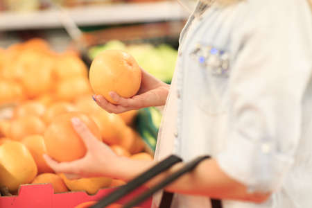 Female hands hold two juicy and fresh oranges. Delicious tropical fruits. Close-up of two oranges. Food concept.の写真素材