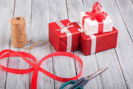 Beautiful gift boxes with a red and white bow on a wooden background.