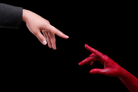 Human hands painted in red are posing on a black background.の写真素材