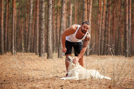 Handsome young man with a labrador outdoors in the forest.の写真素材