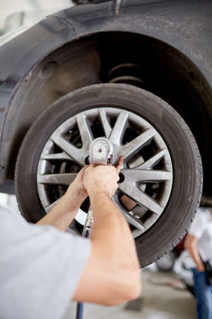 The mechanic twists the wheels of the car on the liftの写真素材