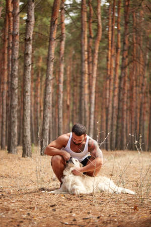 Handsome young man with a labrador outdoors in the forest.の写真素材