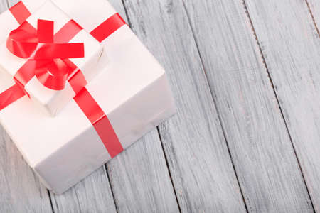 White gift box with a red ribbon on a gray background.の写真素材
