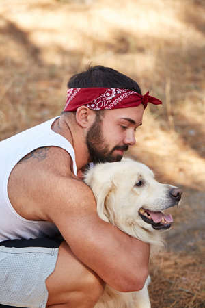 Handsome young man with a labrador outdoors in the forest.の写真素材