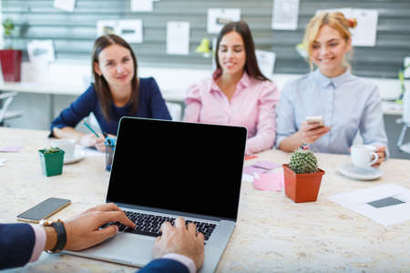 Laptop from the first person on the background of a group of office workersの写真素材