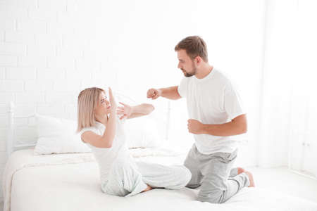 A man wants to hit a girl in bed on a white backgroundの写真素材