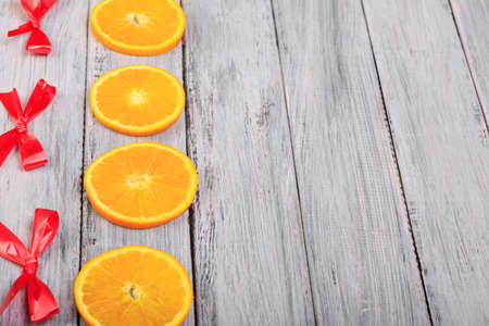Orange slices and red bows on a gray wooden table.の写真素材