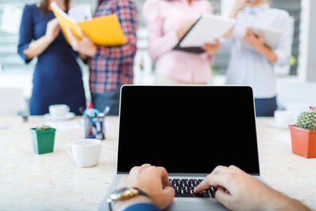 Laptop from the first person on the background of a group of office workersの写真素材